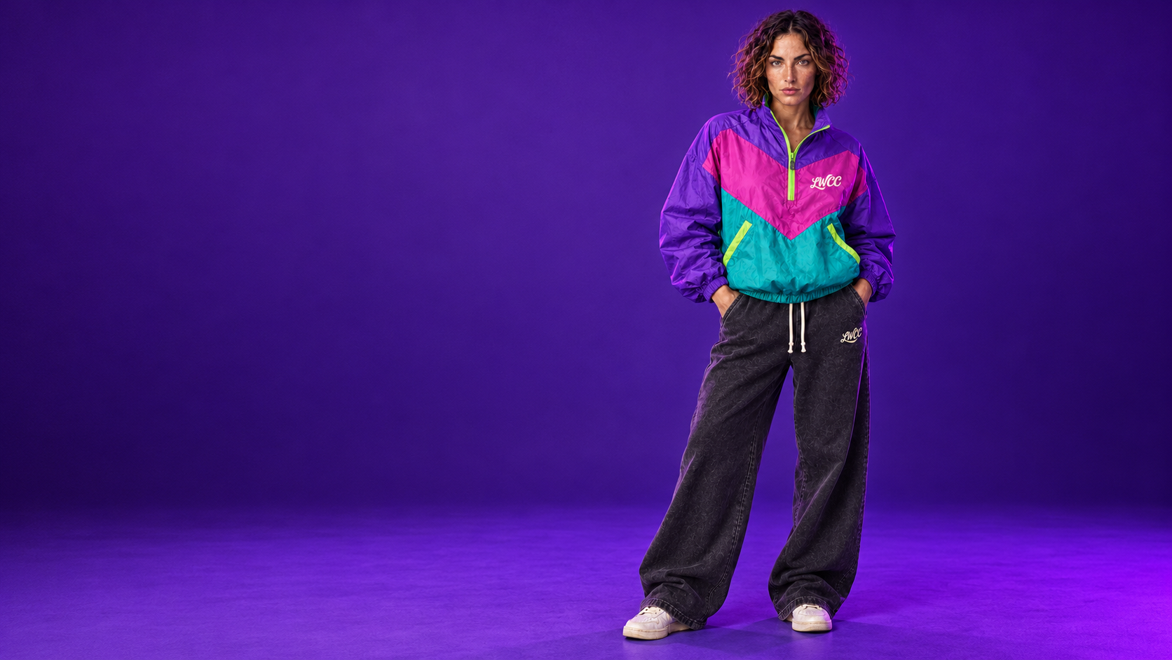 Lost Wight model wearing the purple pink and teal Neon Wave shell jacket with charcoal baggy joggers against violet