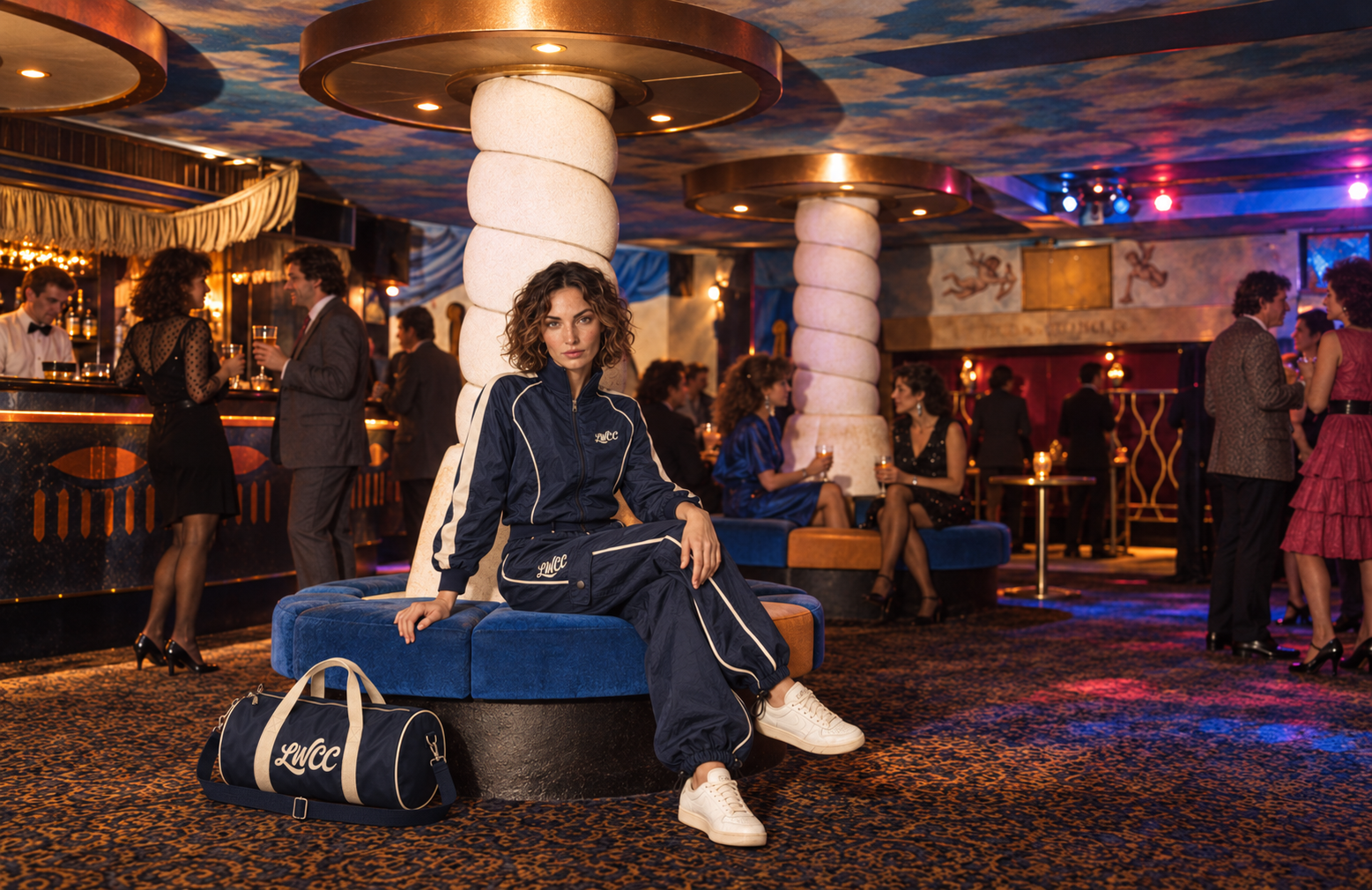 Our model seated with crossed legs in navy Court Piping beside the navy and cream bowling bag